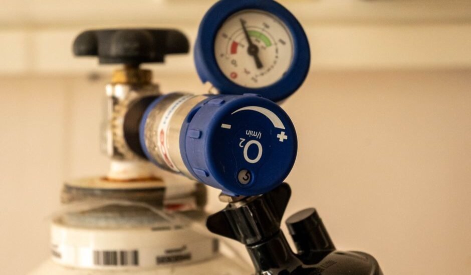 Detailed view of an oxygen tank with a pressure gauge, showcasing medical equipment usage.