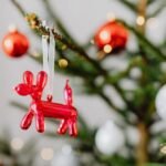 Close-up of a Christmas tree with a red balloon dog ornament, creating a festive holiday atmosphere.