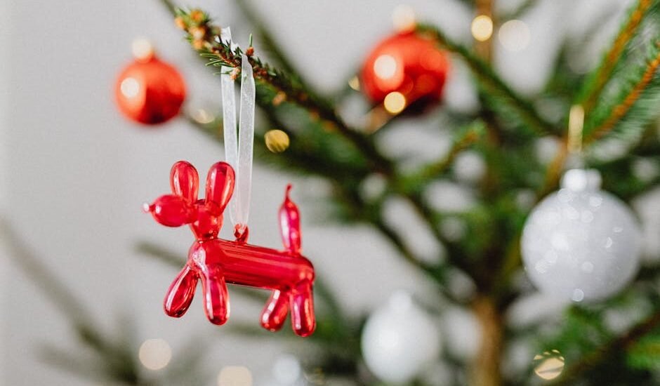 Close-up of a Christmas tree with a red balloon dog ornament, creating a festive holiday atmosphere.