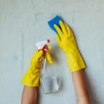 Hands in yellow gloves using a spray bottle and sponge for cleaning, relevant for aquarium air stones maintenance.