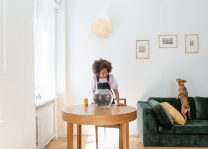 A child looks into a corner fish tank on a table, showcasing stylish aquarium options.