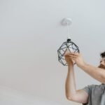 A person installing a geometric light fixture, relevant to plant grow light strips.