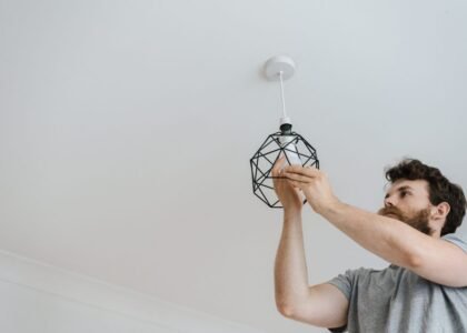 A person installing a geometric light fixture, relevant to plant grow light strips.