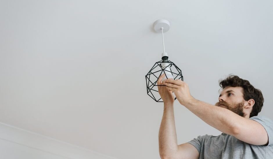 A person installing a geometric light fixture, relevant to plant grow light strips.