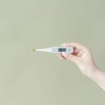 A hand holding a digital aquarium thermometer with a probe, relevant to choosing the right thermometer.