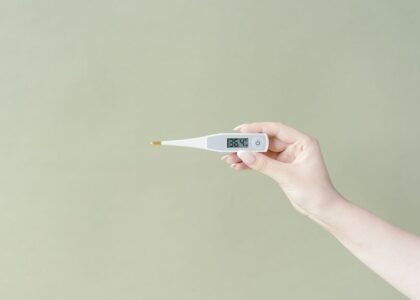 A hand holding a digital aquarium thermometer with a probe, relevant to choosing the right thermometer.