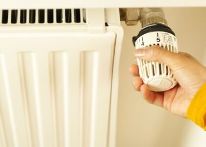 A hand adjusting the temperature dial on an aquarium heater, illustrating how to set heater temperature.