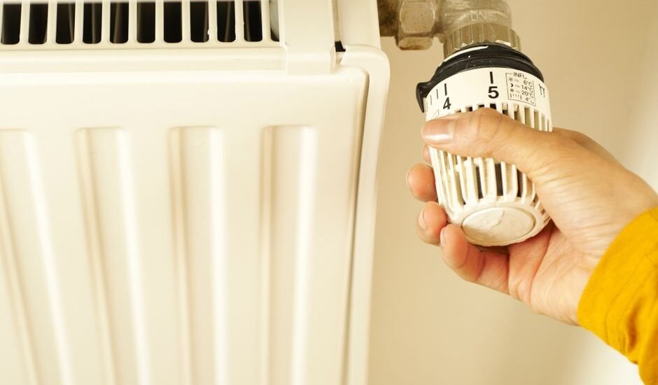 A hand adjusting the temperature dial on an aquarium heater, illustrating how to set heater temperature.