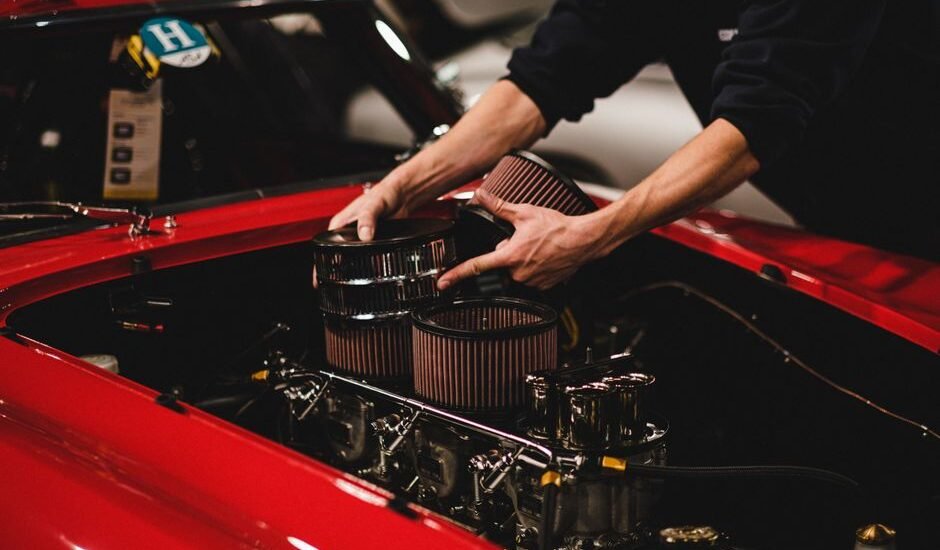 A person installing components in a car engine, illustrating the setup process for a double sponge filter.