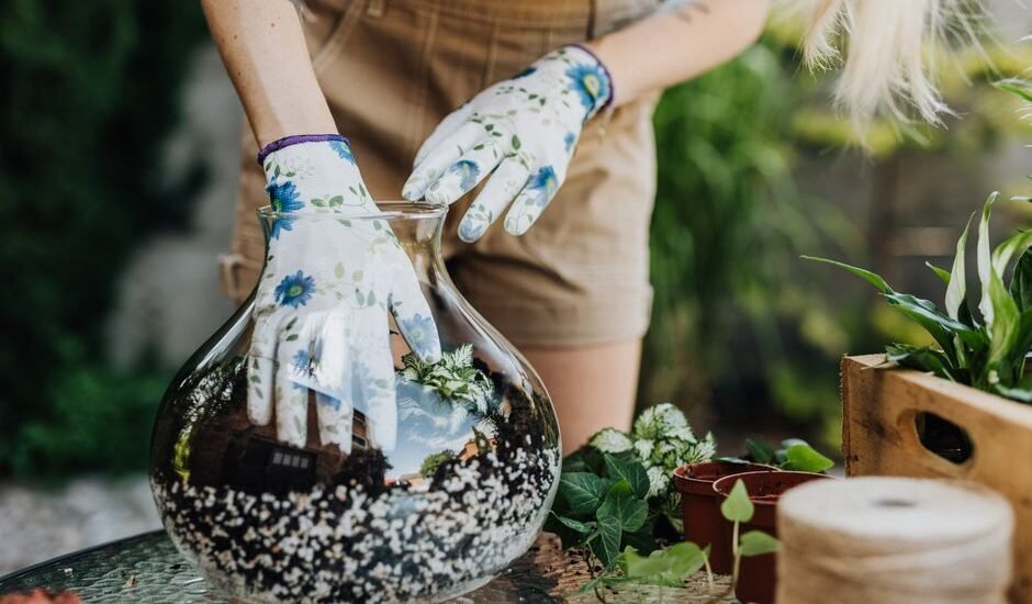 A person in gloves adding substrate to a glass aquarium for planted tanks.