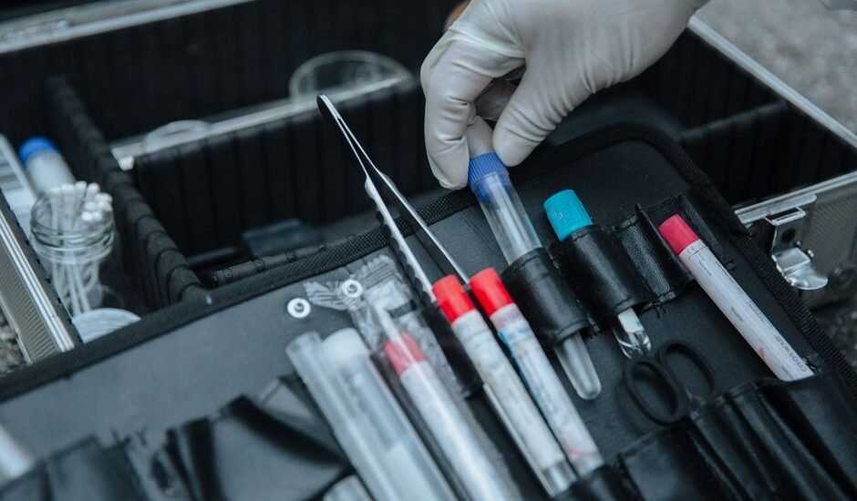 A hand in a glove holds a test tube from a water test kit, relevant to aquarium water test kit accuracy.